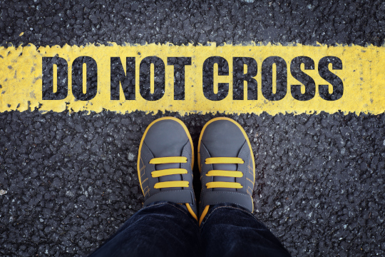 Feet standing next to Do Not Cross line